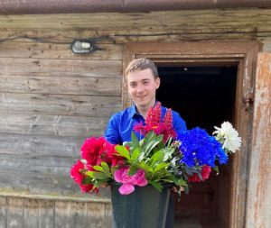 En tonårs pojke från balvi som håller i blommor han fått från skol avslutningen.