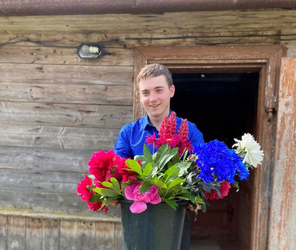 En tonårs pojke från balvi som håller i blommor han fått från skol avslutningen.