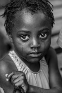 En svart vit bild av en ledsen flicka från Haiti.