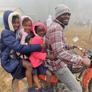 En bild av en far och tre barn från Haiti, bois negresse på en gammal motorcykel som kör sina barn till skolan.