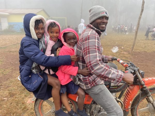 En bild av en far och tre barn från Haiti, bois negresse på en gammal motorcykel som kör sina barn till skolan.